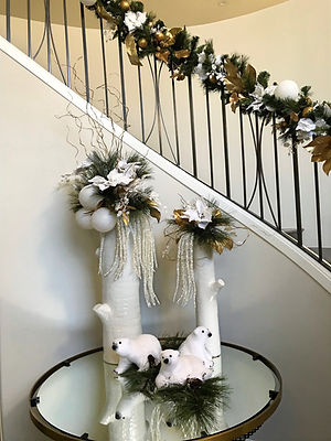 Christmas arrangements in white, ceramic birch logs with polar bear arrangement and stair garland